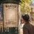 Litfaßsäule in Paris mit einem WANTED-Plakat, dessen Porträtfeld leer ist – Passanten schauen ratlos